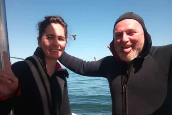Deux plongeurs souriants sur un bateau en mer, journée ensoleillée