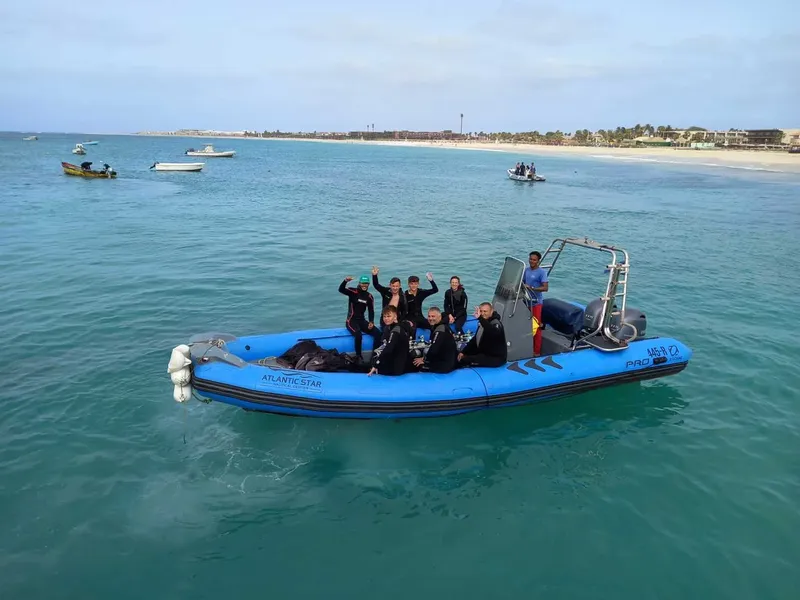 Groupe de plongeurs souriants sur un bateau semi-rigide bleu en mer