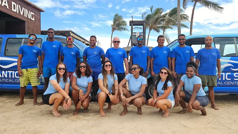 Groupe de personnes souriantes posant devant des véhicules sur une plage