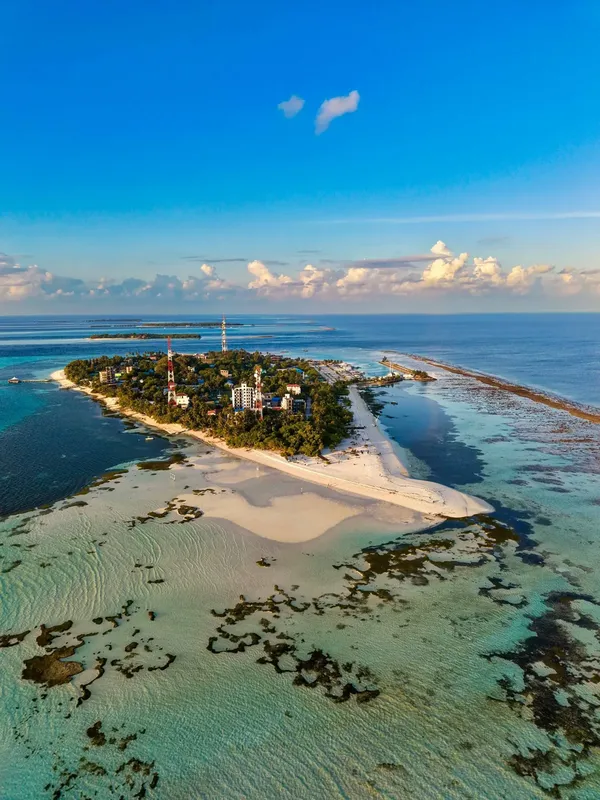 Île tropicale avec plage de sable blanc et bâtiments au centre