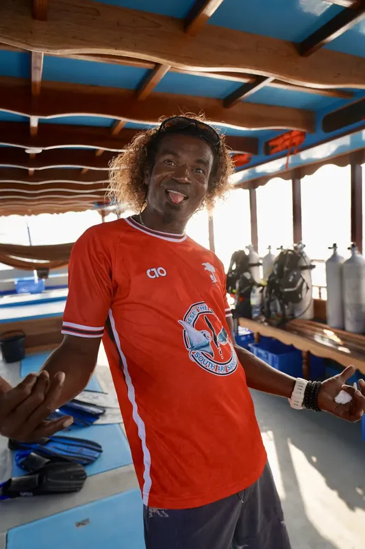 Homme souriant sur un bateau de plongée avec des bouteilles