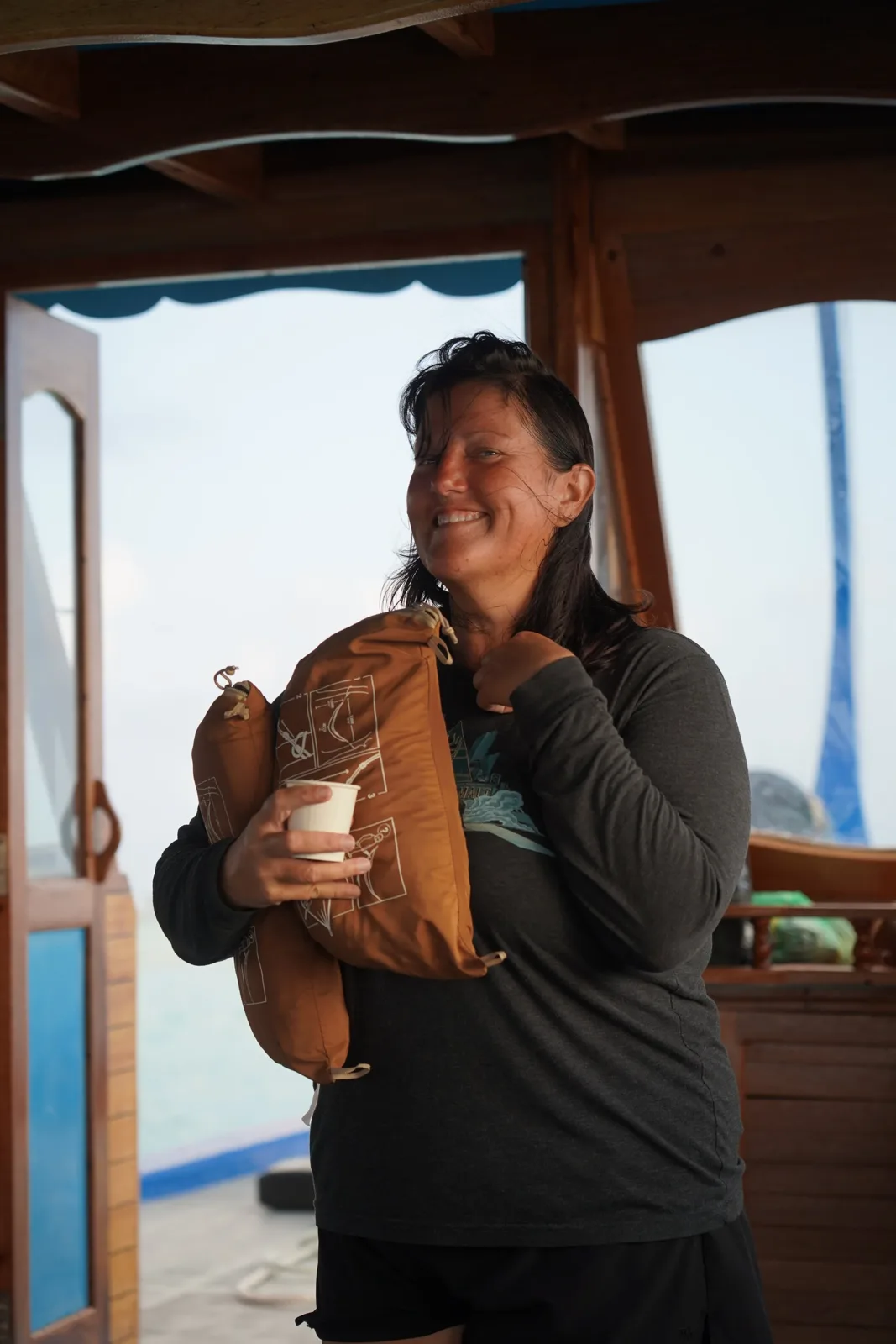 Femme souriante tenant un sac et une tasse sur un bateau