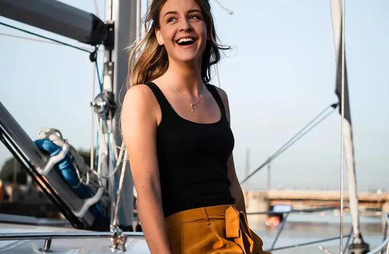 Jeune femme souriante sur un bateau en mer, regardant vers l'avant