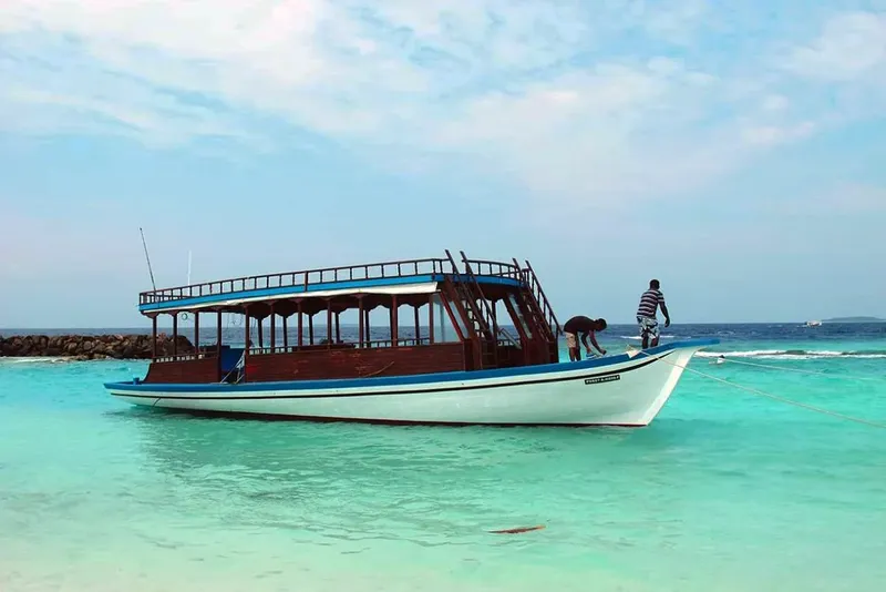 Bateau de plongée blanc et bleu, personnes à bord, eau turquoise