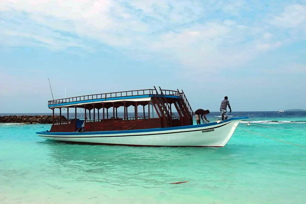 Bateau de plongée blanc et bleu, personnes à bord, eau turquoise