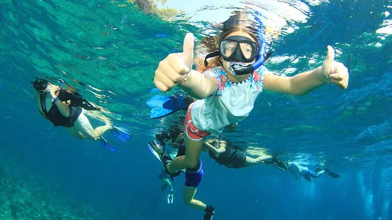 Plongeurs souriants avec des pouces levés sous l'eau turquoise
