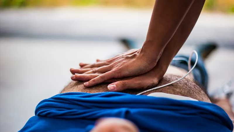 Mains pratiquant un massage cardiaque sur une personne allongée