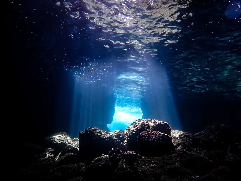 Rayons de lumière traversant une grotte sous-marine rocheuse et bleue