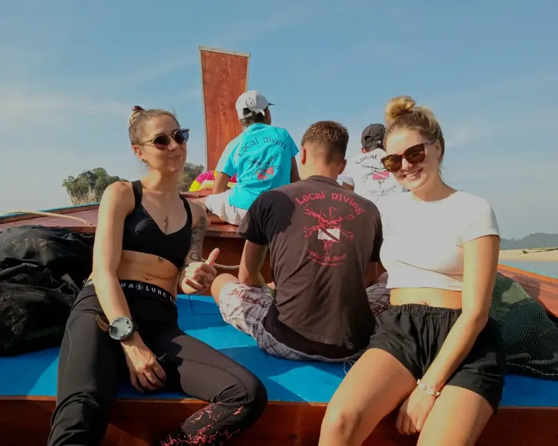 Plongueurs souriants sur un bateau traditionnel en direction du site