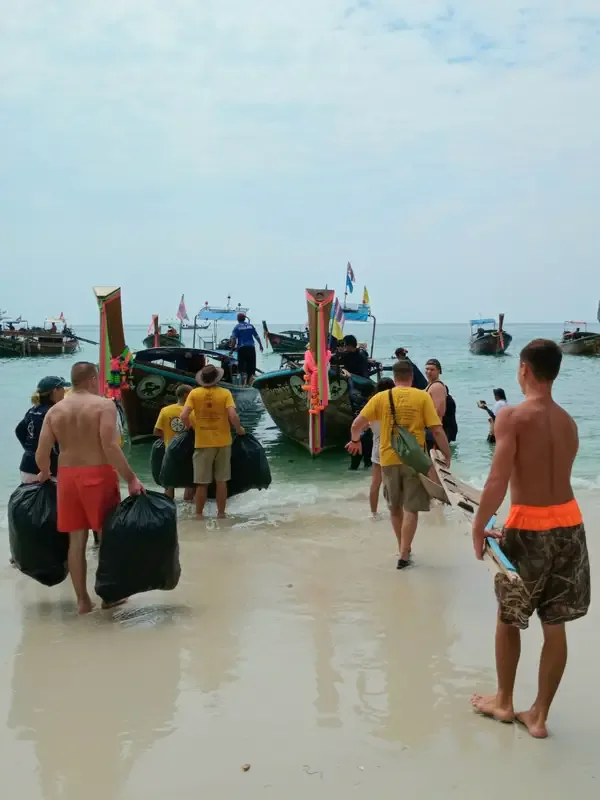 Plage avec des personnes transportant des sacs et des planches