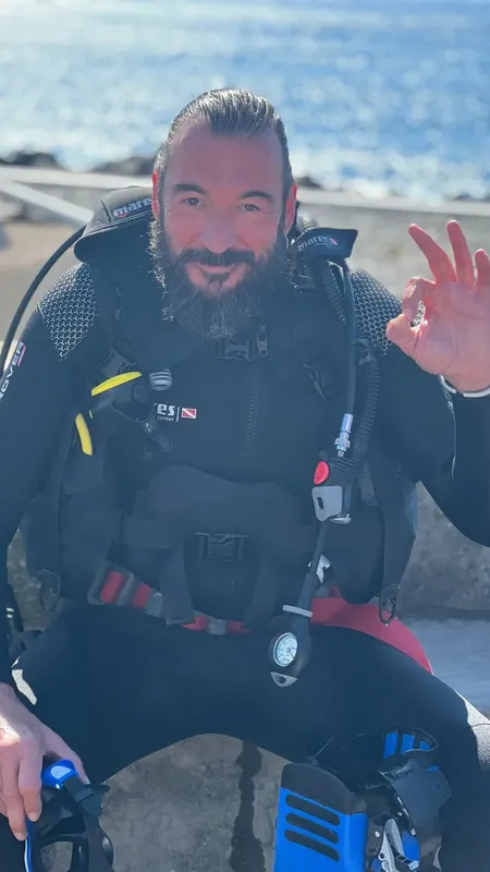 Plongeur souriant avec son équipement complet sur un quai ensoleillé