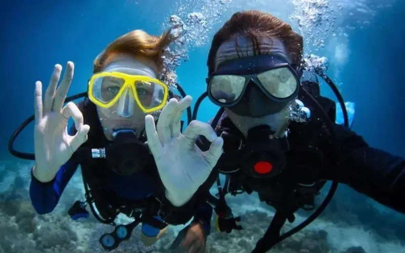Deux plongeurs souriants font le signe OK sous l'eau