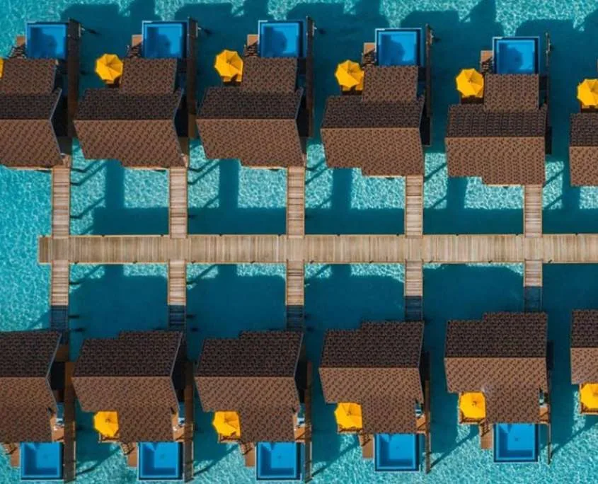 Vue aérienne de bungalows sur pilotis au-dessus d'eau turquoise