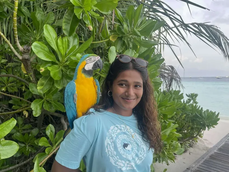 Femme souriante avec un ara bleu et jaune sur l'épaule
