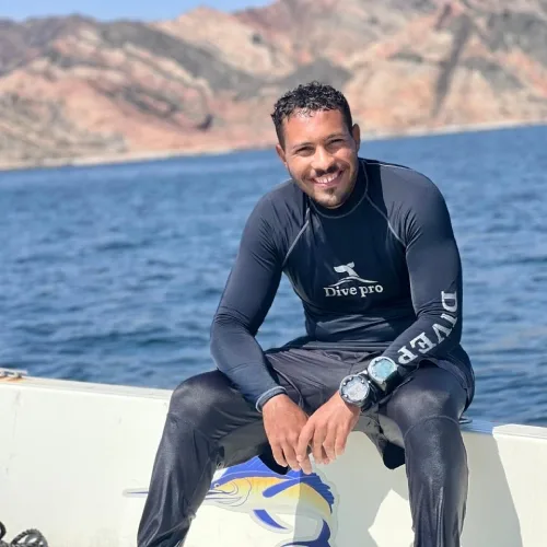 Un plongeur souriant assis sur la proue d'un bateau en mer