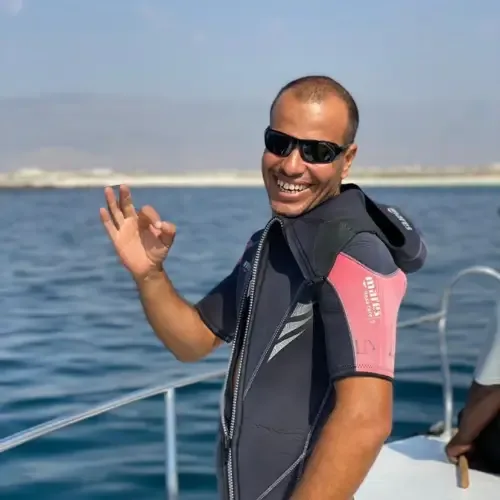 Homme souriant sur un bateau, portant un gilet de plongée