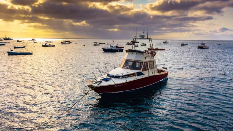 Bateau de pêche rouge amarré sur une mer calme au coucher du soleil