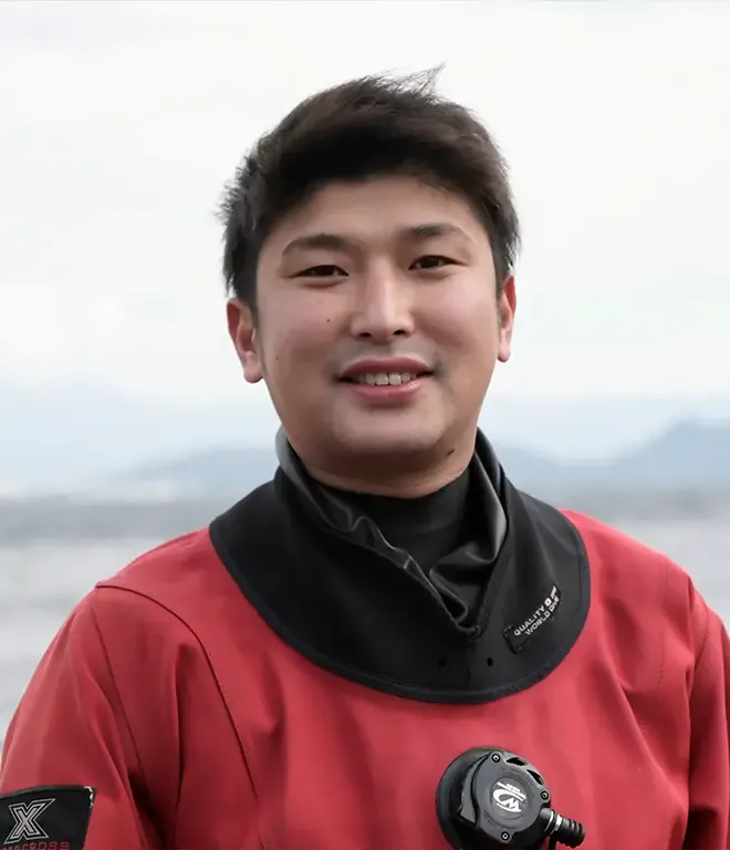 Portrait d'un plongeur souriant portant une combinaison rouge et du matériel