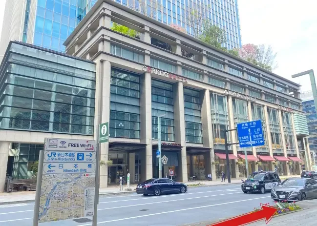 Façade d'un bâtiment moderne avec des voitures et des passants