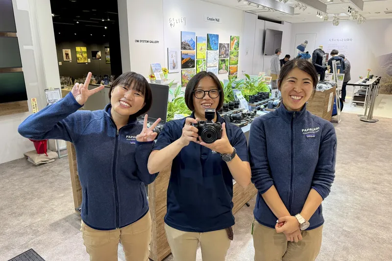 Trois femmes souriantes posent avec un appareil photo dans un magasin
