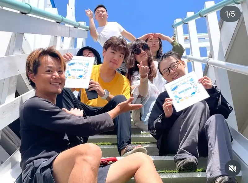 Groupe de personnes souriantes tenant des certificats de plongée en extérieur
