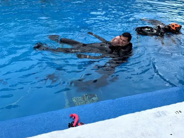 Deux plongeurs en combinaison flottent dans une piscine bleue claire