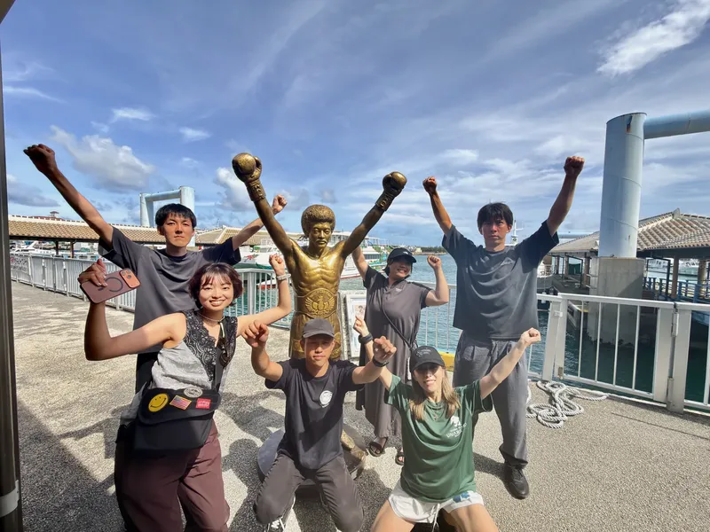 Groupe de personnes souriantes posant avec une statue de Bruce Lee
