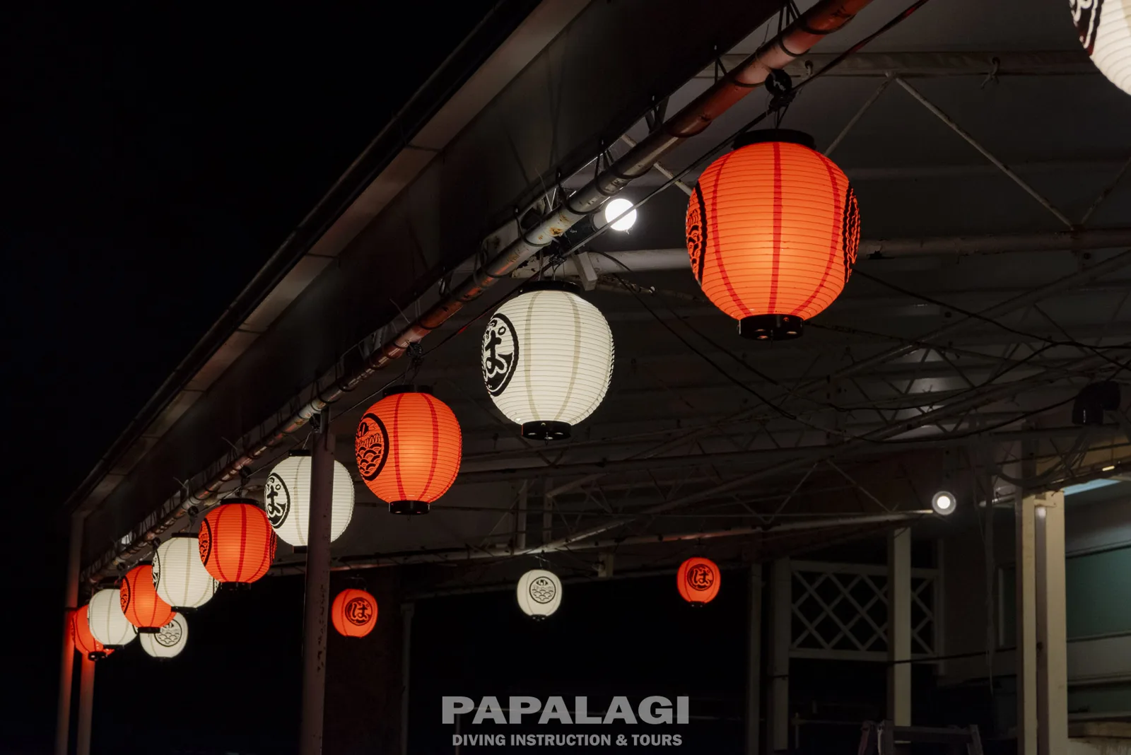 Lampions rouges et blancs illuminent la terrasse d'un centre de plongée