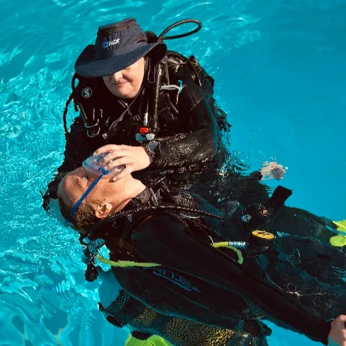 Deux plongeurs en combinaison effectuent un exercice de sauvetage en piscine