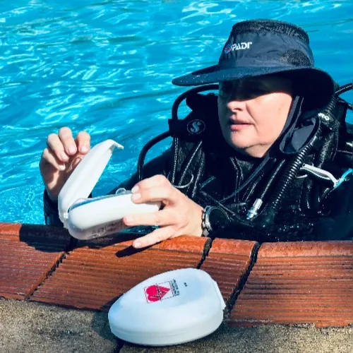 Plongeuse vérifiant son ordinateur de plongée au bord d'une piscine