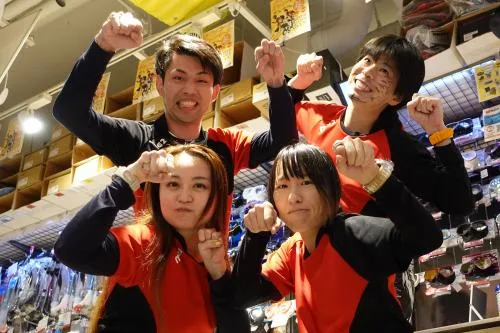 Quatre personnes souriantes lèvent les poings dans un magasin de plongée