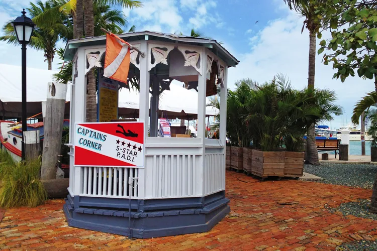 Kiosque blanc et rouge avec enseigne et drapeaux de plongée PADI