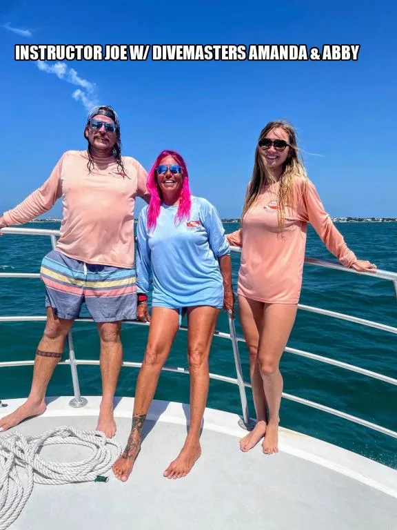 Trois personnes souriantes sur un bateau en mer, ciel bleu
