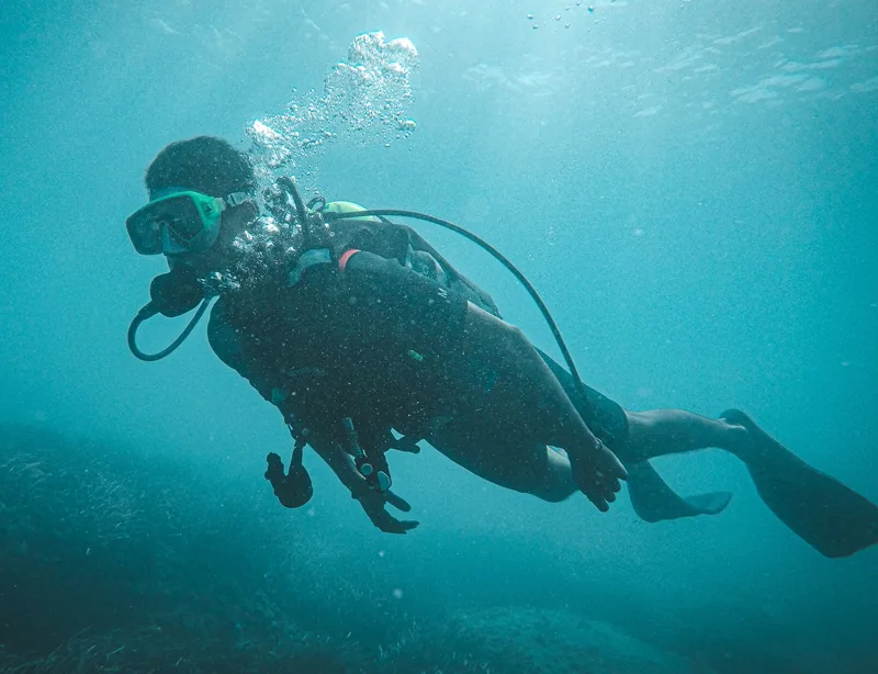 Plongeur en scaphandre explore les fonds marins dans une eau turquoise