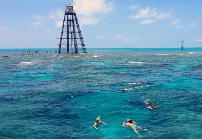 Plusieurs personnes pratiquent le snorkeling dans une eau turquoise claire