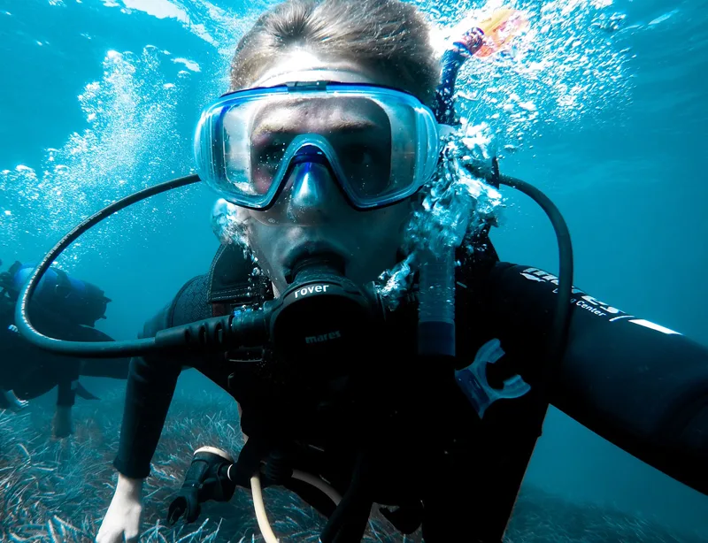 Plongeur avec masque et détendeur, regardant vers la caméra sous l'eau