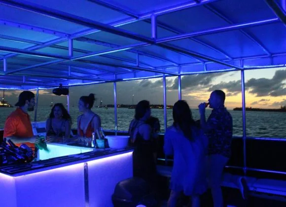 Groupe de personnes sur un bateau illuminé en bleu au coucher du soleil