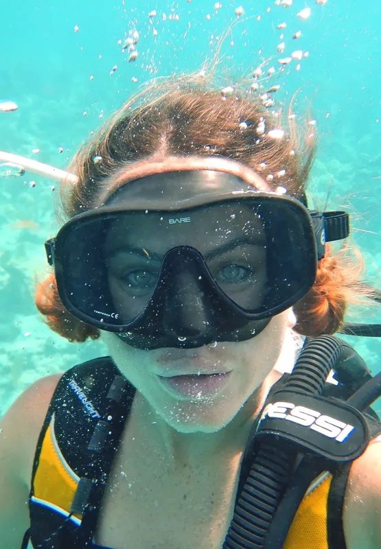 Plongeuse souriante avec masque et détendeur, cheveux flottants dans l'eau