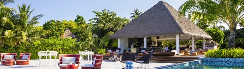 Espace détente extérieur avec mobilier, végétation tropicale et structure couverte