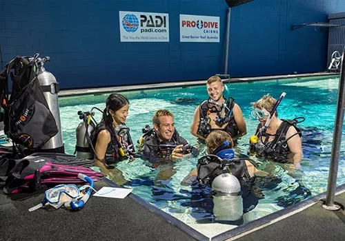 Quatre plongeurs en formation dans une piscine avec équipement complet