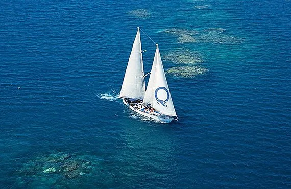 Grand voilier blanc naviguant sur une mer bleue ensoleillée
