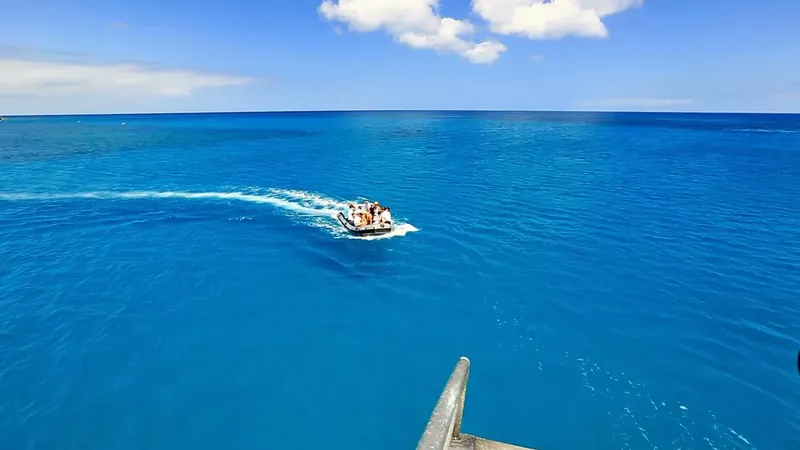 Un bateau semi-rigide navigue sur une mer bleue sous un ciel nuageux