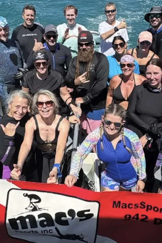 Groupe de plongeurs souriants posant sur un bateau de plongée ensoleillé