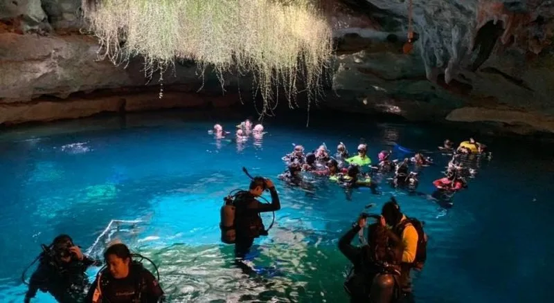 Groupe de plongeurs explore une grotte sous-marine éclairée et spectaculaire