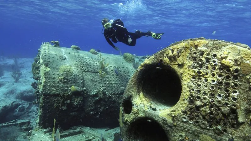Plongeur explorant une épave sous-marine avec des coraux et poissons