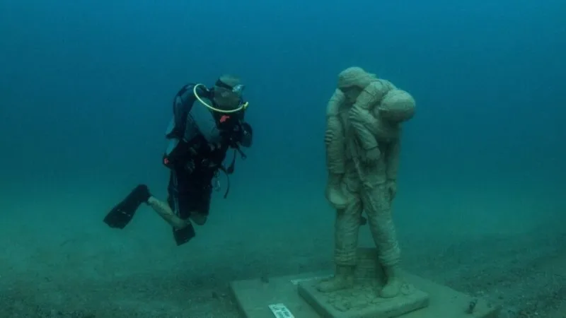 Plongeur explorant une statue sous-marine dans une eau claire