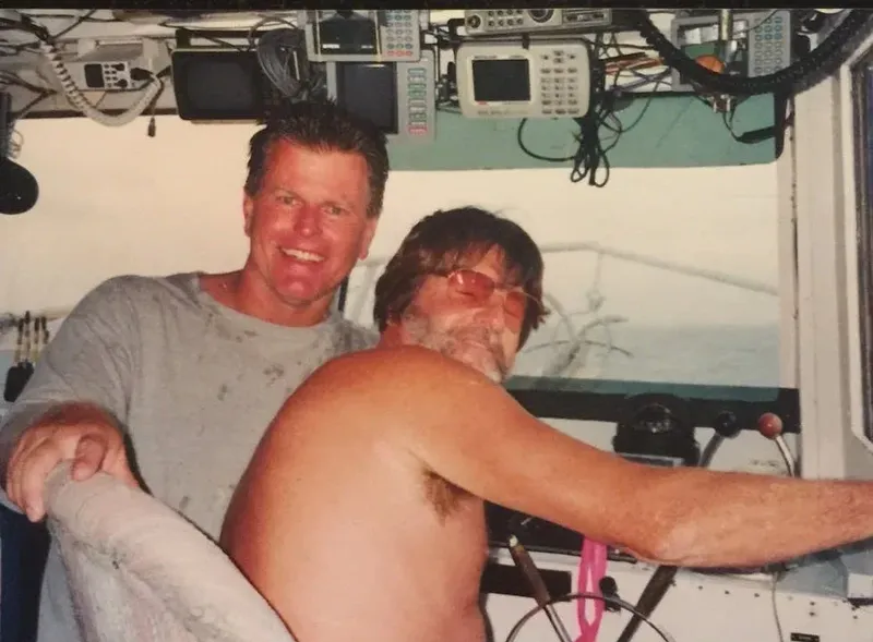 Deux hommes souriants posent sur un bateau de plongée ensoleillé