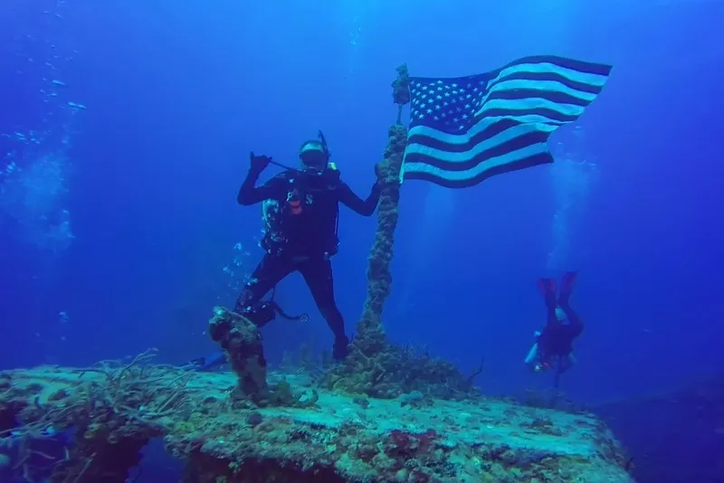 Deux plongeurs sous l'eau, un tenant un drapeau américain