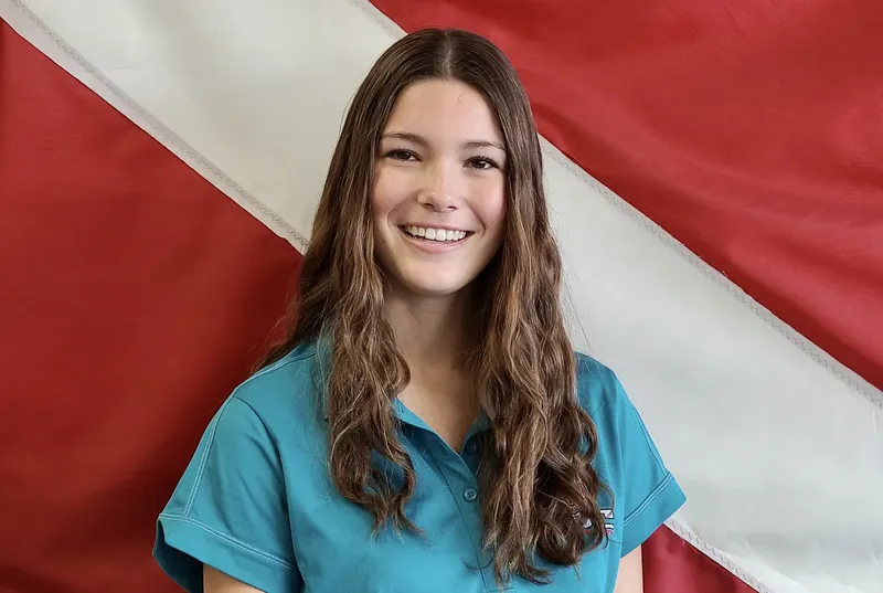 Jeune femme souriante devant un drapeau rouge et blanc