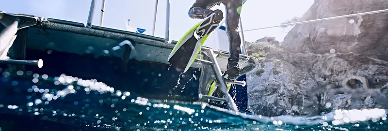Plongeur s'apprête à sauter d'un bateau dans une mer claire